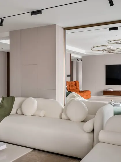 A view showing the relationship between different zones in the living area. The reflection in the glass partition reveals the entertainment section, demonstrating how we create layered, multi-functional spaces that remain visually connected and harmonious.