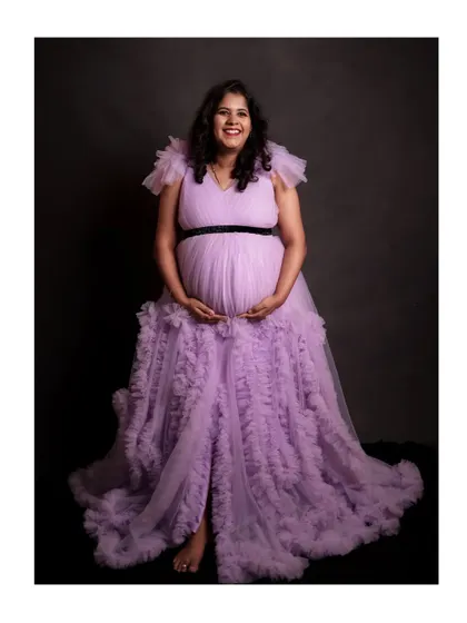 A joyful shot of the mother-to-be in the lavender ruffle gown. The gown has a high slit and layers of soft tulle for a very photogenic look.