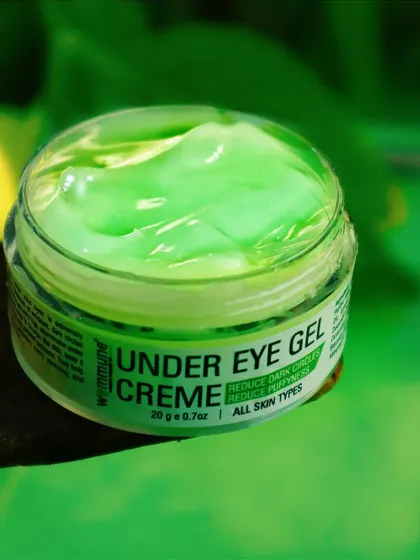 A close-up of the Wommune under-eye gel, focusing on its smooth, cooling texture against a vibrant green backdrop.