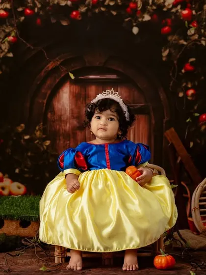 Another regal pose from our little Snow White, sitting patiently in her fairytale scene surrounded by apples and rustic props.