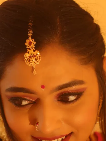 A detailed shot of the eye makeup. You can see the blend of warm eyeshadows and the precise eyeliner that defines the eye shape, creating a look that is both soft and impactful.