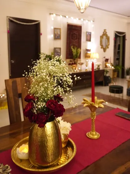 My dining table, set for a Diwali feast. The red runner, brass vase, and candles create a rich and celebratory look.