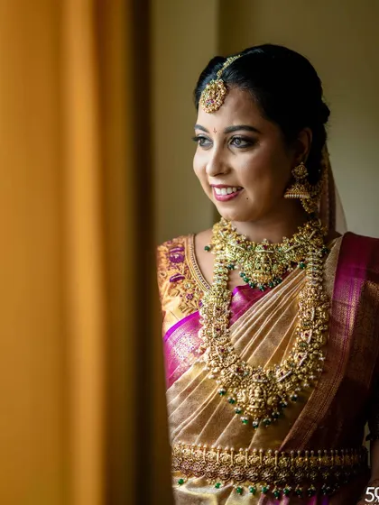 A beautiful candid shot of the bride looking out a window. The natural light highlights the flawless airbrush makeup and her radiant smile.