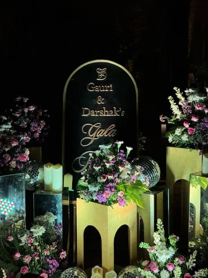An elegant welcome sign for a gala dinner. The black and gold design, surrounded by floral arrangements, disco balls, and candles, set a sophisticated and celebratory tone for the evening.