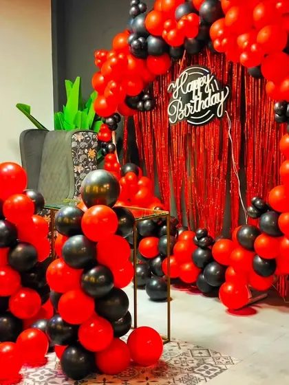 A bold red and black balloon arch with a fringe curtain backdrop. This setup is perfect for creating a dramatic and high-energy photo corner for a birthday party.