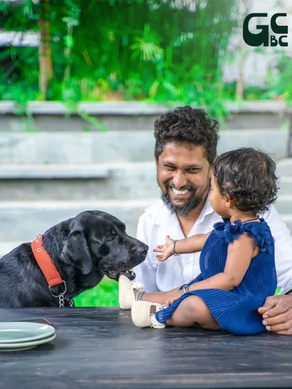 A heartwarming moment between a father, his baby, and their loving black labrador.