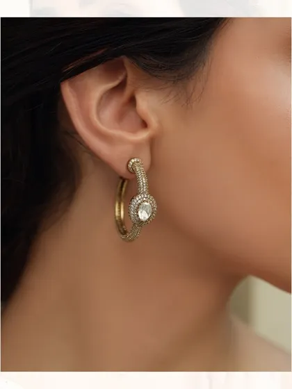 A modern classic, these hoop earrings are studded with polki diamonds and feature a central sparkling motif.