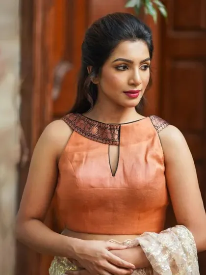 A sleeveless peach-colored blouse with a keyhole neckline, perfect for a subtle, elegant look.