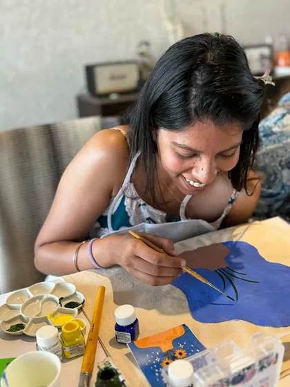 A guest smiling as she paints her tote bag. Our workshops are all about enjoying the process and having fun.