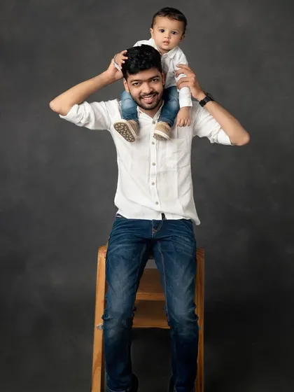 A father's pride and joy. This classic studio portrait of a dad with his son on his shoulders is a timeless image of strength, love, and fun.