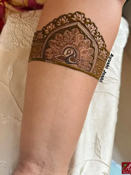 A close-up of a traditional arm band, showcasing a simple yet elegant peacock motif.