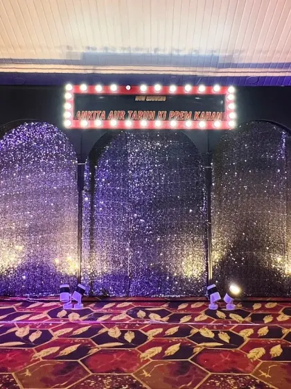 A glittering sangeet stage with a Bollywood theme, featuring arched sequin backdrops and a marquee sign.