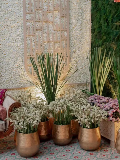 A detail shot of a seating area with brass pots filled with fresh tuberoses. The combination of metallic accents and fragrant white flowers is a classic and elegant choice.