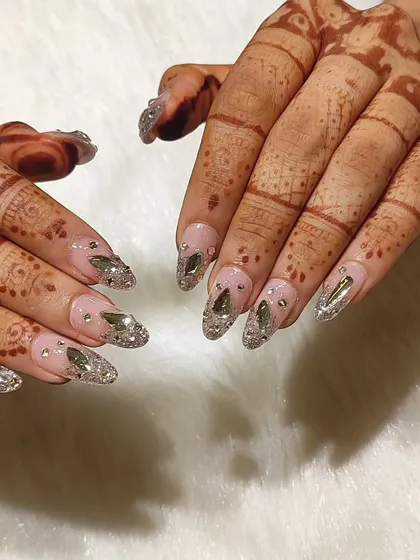 For the bride who wants to be the main character. This wedding nail set features a sheer pink base with a cascade of silver glitter and hand-placed, multi-faceted crystals for maximum sparkle that complements your mehendi.