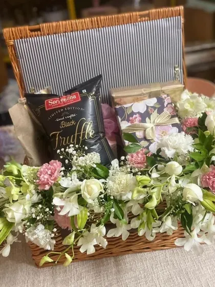 I love incorporating fresh flowers into my hampers to add a touch of natural beauty. This wicker basket is filled with white and pink blooms, gourmet truffle chips, and other gift boxes.