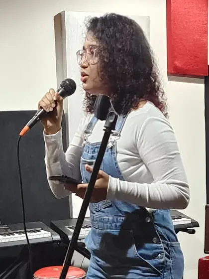 An action shot from an open mic night. Whether it's a big stage or a small room, I pour my heart into every performance. You can see me here with my keyboard and mic, ready to share some music.