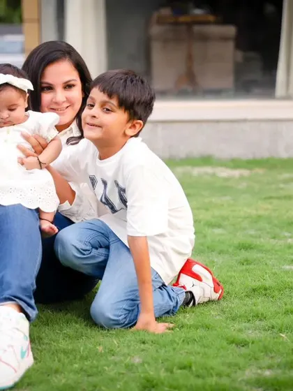 A mother with her two children, a baby and a young boy, enjoying a moment together on the grass.