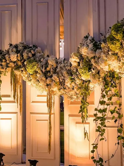 The floral garlands seen at night, softly lit to highlight their texture and beauty. The warm lighting adds a romantic touch to the grand entrance.