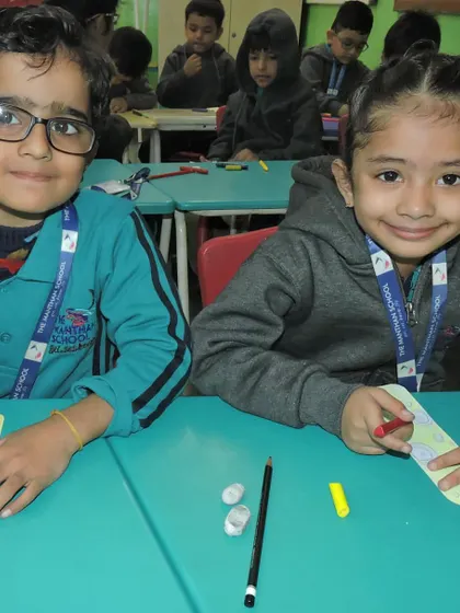 Two smiling students work together on their coloring project, fostering a sense of community and shared purpose.