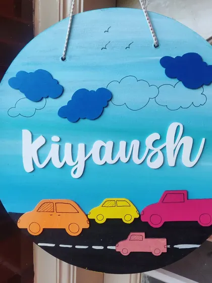 For the little car enthusiast, this nameplate features a road with colorful cars against a bright blue sky. The 3D clouds and laser-cut name add a fun, layered effect to the design.