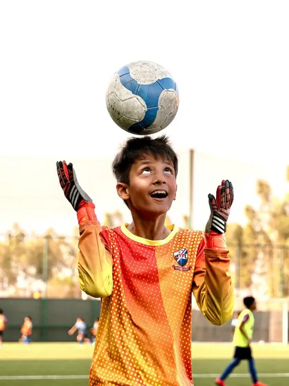 A goalkeeper having a fun moment during practice, balancing the ball on his head.