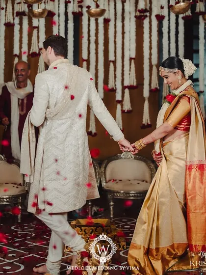 A beautiful moment from a traditional South Indian wedding. The mandap is decorated with red and white floral garlands, with rose petals showering the happy couple as they complete their rituals.