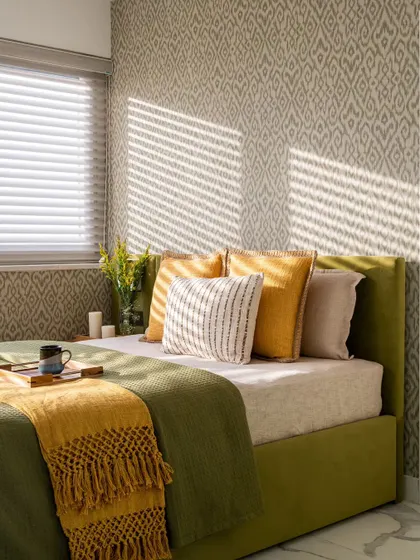 A sun-drenched room in a Jaipur vacation penthouse, featuring a vibrant Ikkat print wallpaper. The citric green bed and mustard yellow throw create a zesty, energetic feel, perfect for a holiday home.