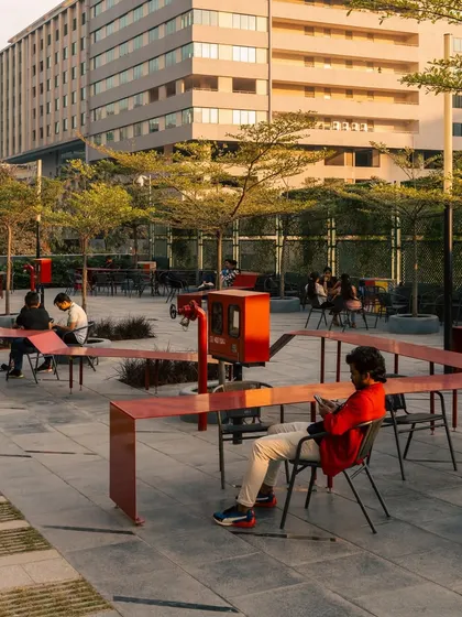 The Red Ribbon Plaza in use. The design encourages various forms of social interaction, from individual work to group conversations. It activates the outdoor space of the campus, fostering a sense of community and well-being among employees.