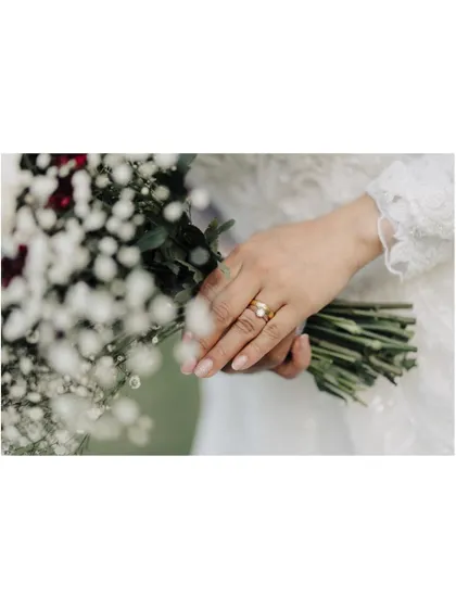 A delicate shot focusing on the bride's hand, showing her wedding ring as she holds her bouquet. It’s a simple, elegant photo that symbolizes her new marital status.