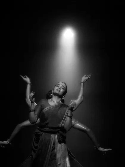 A striking image from 'Naga Mandala' where a dancer appears to have multiple arms, created by the movement of other performers in the shadows.