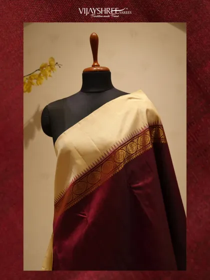 A full view of the cream and maroon saree on a mannequin, a classic and sophisticated choice.