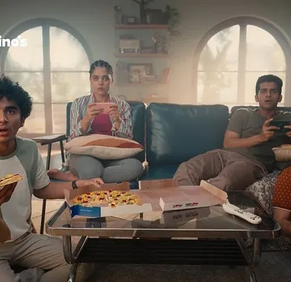 A wider shot of the friends enjoying Domino's pizza. The overall art direction and wardrobe styling work together to create a warm, inviting, and fun atmosphere.