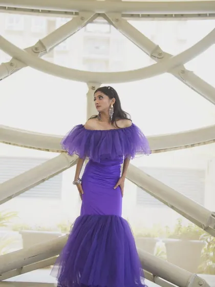 A full-length shot showing the dramatic mermaid silhouette and ruffled hem of this stunning purple gown.