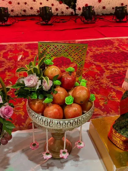 A fruit platter of pomegranates, decorated with small green flowers and a delicate floral arrangement.