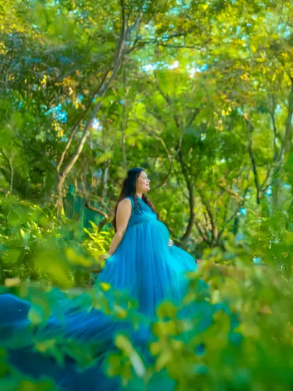 A fairytale moment captured in the heart of nature. This mother-to-be looks serene and beautiful in a flowing blue gown, surrounded by the lush greenery of a Bangalore garden.