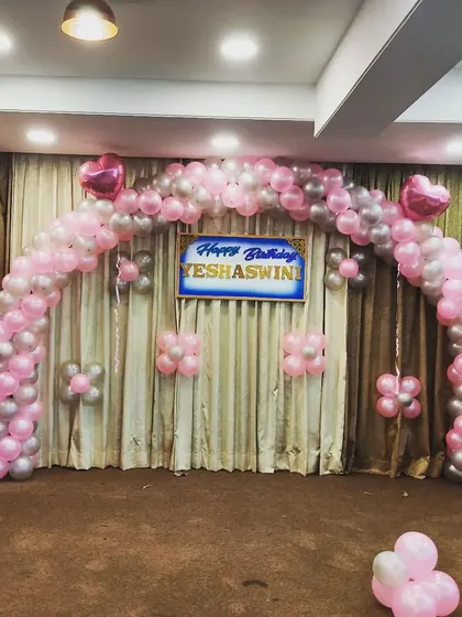 A classic Minnie Mouse themed balloon arch decoration. This setup uses pink and silver balloons to create a wide arch, with two large Minnie Mouse balloon figures standing guard on each side.
