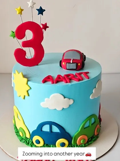 Zooming into another year. This colorful cake is themed around cars and is perfect for a 3-year-old who loves things that go. The bright blue sky and fondant cars create a playful scene.