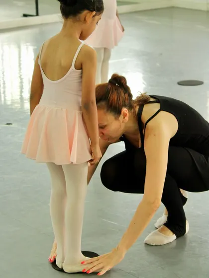 Perfecting the first position is a crucial early step. An instructor provides a hands-on correction, ensuring the student's feet are placed correctly to build proper technique from the ground up.