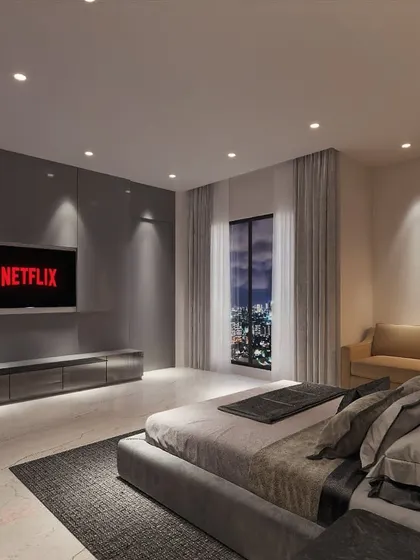 The perfect bedroom for a movie lover. The design features a large screen, a minimalist TV unit, and strategically placed spotlights to create a cozy, theater-like experience with a view of the city lights.