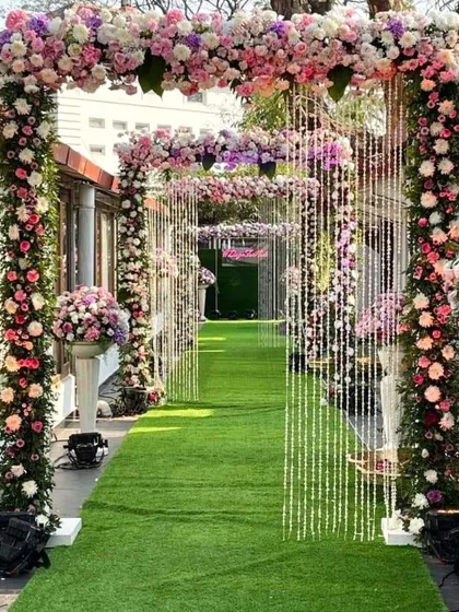 This beautiful garden path is lined with arches of pink and purple flowers, with crystal strings hanging down for a touch of sparkle. The green grass aisle creates a fresh and natural feel.
