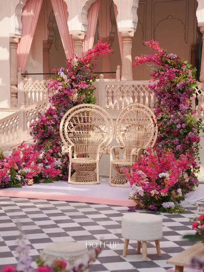 The couple's seating for the welcome lunch, featuring peacock-style cane chairs framed by arches of bougainvillea. The design is a perfect blend of traditional Rajasthani elements and modern aesthetics.