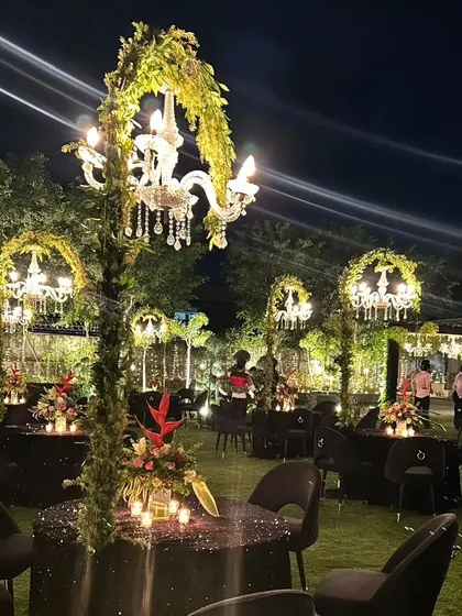 Another view of the enchanting outdoor dinner setup, showing the arrangement of round tables, each with its own stunning chandelier centerpiece.