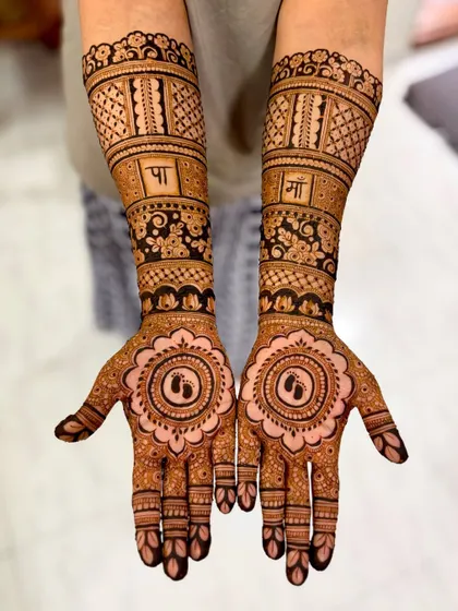 A clear view of the baby shower mehendi with "Pa" and "Ma" in Hindi and baby feet mandalas.