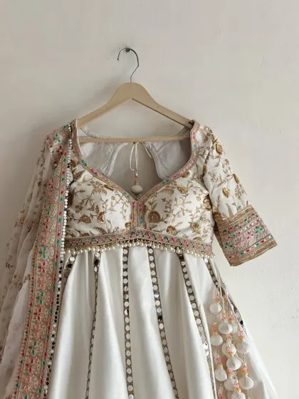 A detailed shot of the front of the blouse and the mirror-work on the lehenga, showcasing the fine craftsmanship.