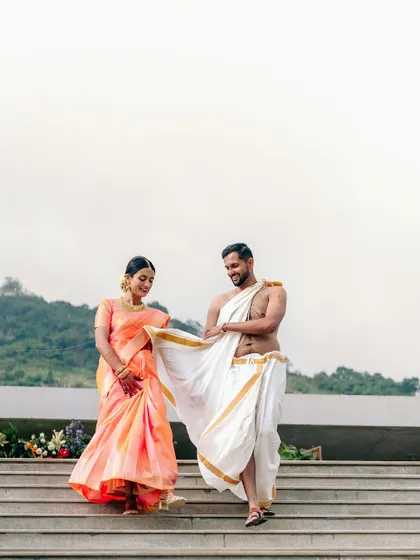 The couple shares a playful moment while walking down the steps at Amita Rasa, Bangalore, after their traditional ceremony.