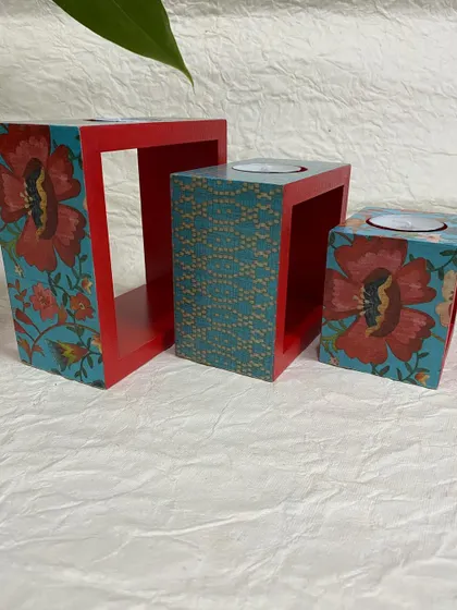 A beautiful tea-light candle holder set with a red and teal floral design. These are made from engineered wood and are very durable.
