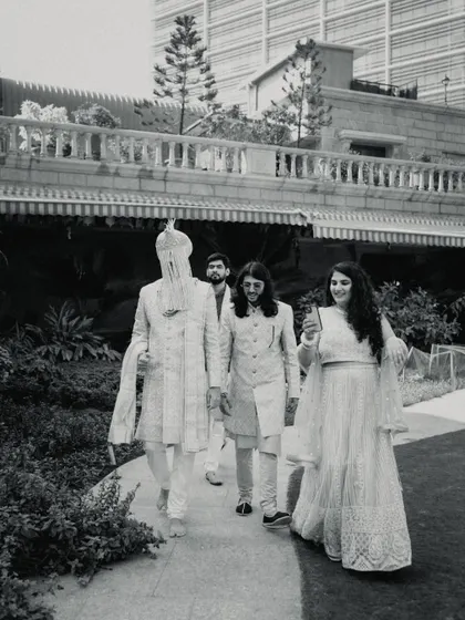 A candid black and white shot of the groom and his party walking through the venue, capturing a relaxed, behind-the-scenes moment.