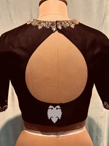 The back of a black silk blouse with a keyhole cutout and a jeweled border.