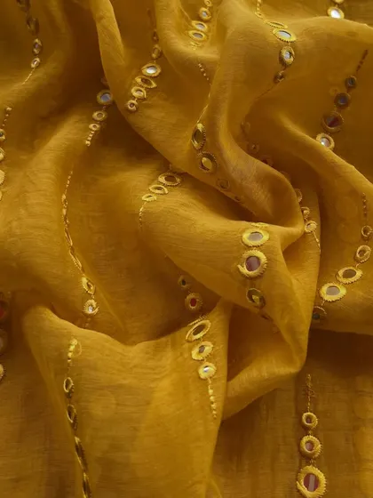 A close-up of our mirror-work Mul Chanderi in a rich mustard color, showcasing the festive and celebratory feel of the fabric.