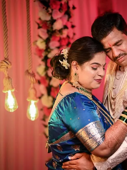 An emotional and tender portrait of a couple in a close embrace. The warm, soft lighting from the hanging bulbs adds to the romantic and intimate atmosphere of the wedding day.